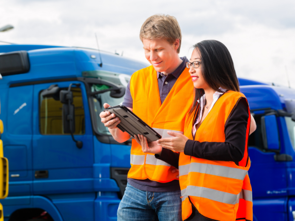 Two people in high vis jackets next to a truck.